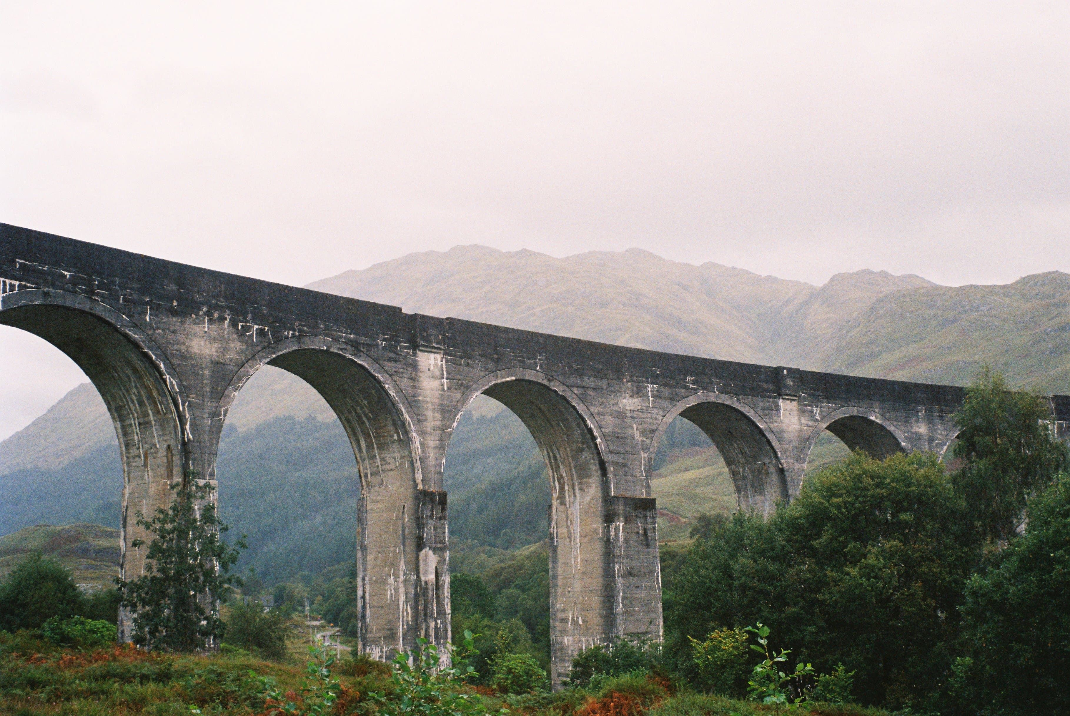 A large stone viaduct, with foliage visible between the archways.